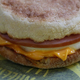 Close-up of an Egg McMuffin from the side, with ham, egg, and melting cheese visible